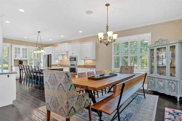 a very nice looking kitchen with granite countertop a stove a sink a dining table and chairs with wooden floor