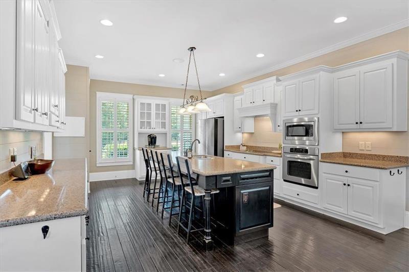 1021 Avery Road Canton, GA 30115 - Photo 14 of 70 a kitchen with stainless steel appliances granite countertop a stove top oven a refrigerator a sink and a dining table with wooden floor