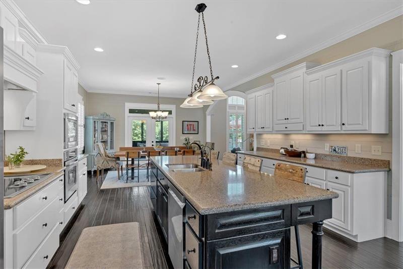 1021 Avery Road Canton, GA 30115 - Photo 15 of 70 a very nice looking kitchen with granite countertop a stove a sink a dining table and chairs with wooden floor