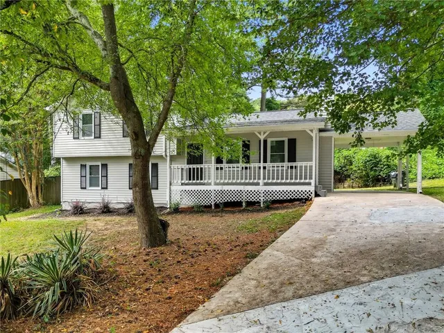 a front view of a house with a garden and trees