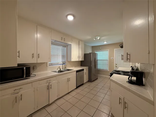 a kitchen with a sink dishwasher and white cabinets