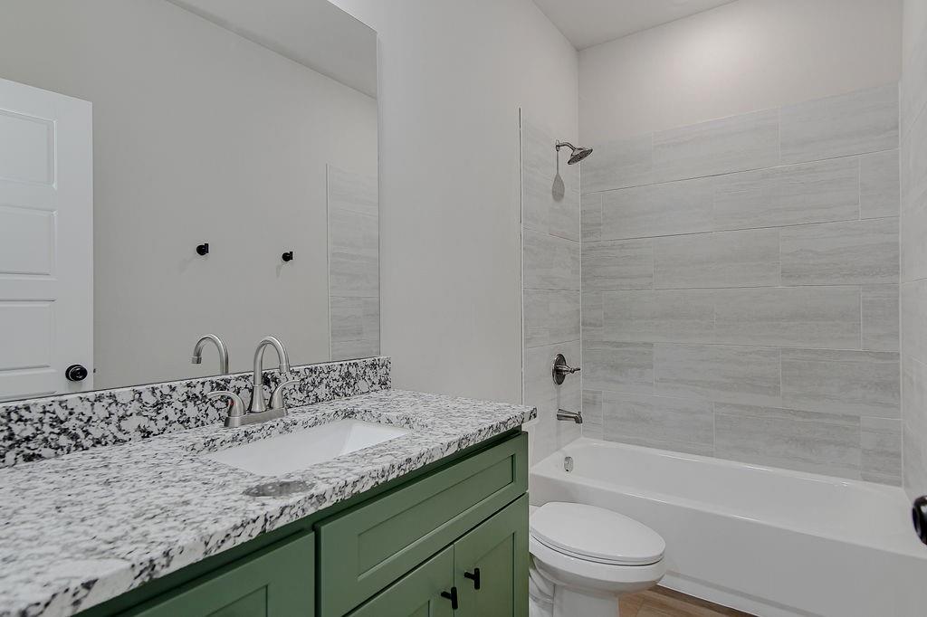 2729 Finley Street Fort Worth, TX 76111 - Photo 27 of 30 a bathroom with a granite countertop sink a toilet and bathtub