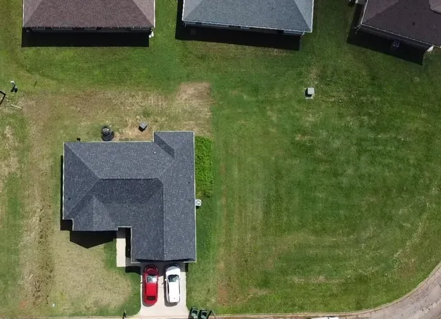 an aerial view of residential houses with outdoor space and trees