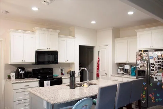 a kitchen with stainless steel appliances granite countertop a refrigerator a sink a stove a microwave and a refrigerator