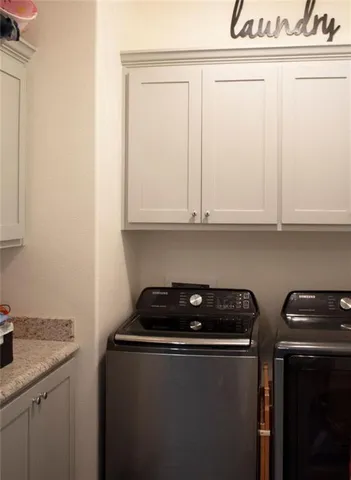 a utility room with granite countertop white cabinets and a stove