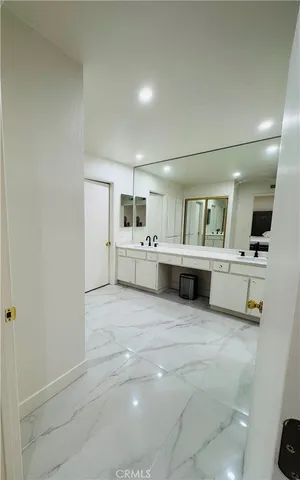 a large white bathroom with a large mirror vanity and refrigerator