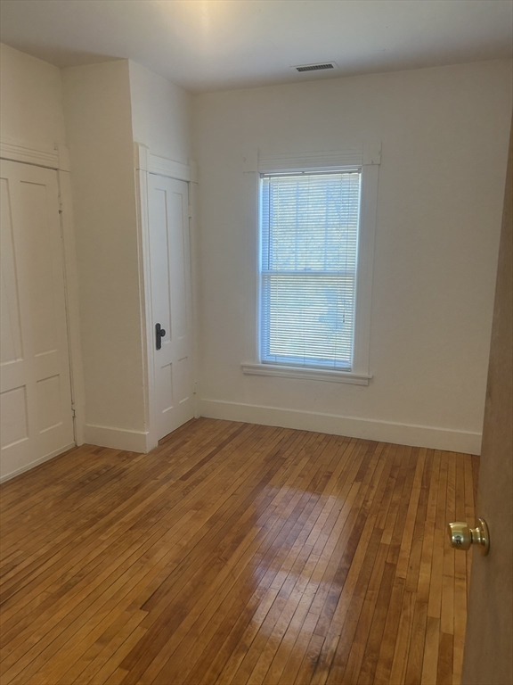 123 Mayfield Street, Unit 2 Worcester, MA 01602 - Photo 11 of 16 an empty room with wooden floor and windows