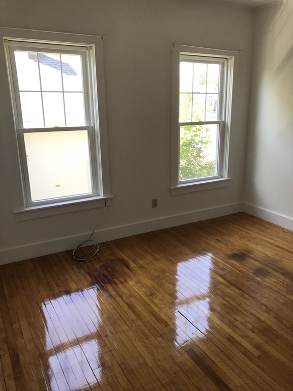 123 Mayfield Street, Unit 2 Worcester, MA 01602 - Photo 6 of 16 an empty room with wooden floor and windows