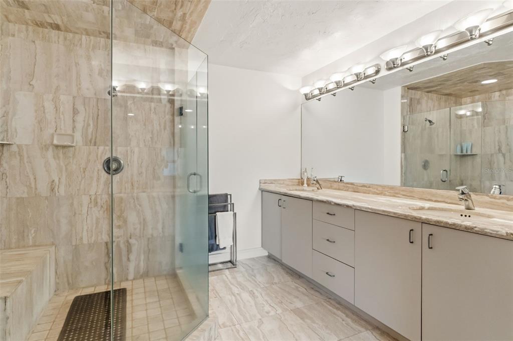 660 Golden Gate Point, Unit 61 Sarasota, FL 34236 - Photo 13 of 44 a spacious bathroom with a granite countertop sink mirror and shower