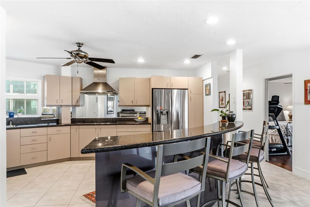 660 Golden Gate Point, Unit 61 Sarasota, FL 34236 - Photo 28 of 44 a kitchen with stainless steel appliances kitchen island granite countertop a table chairs in it and wooden floors