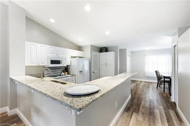 a kitchen with kitchen island granite countertop a sink cabinets and wooden floor