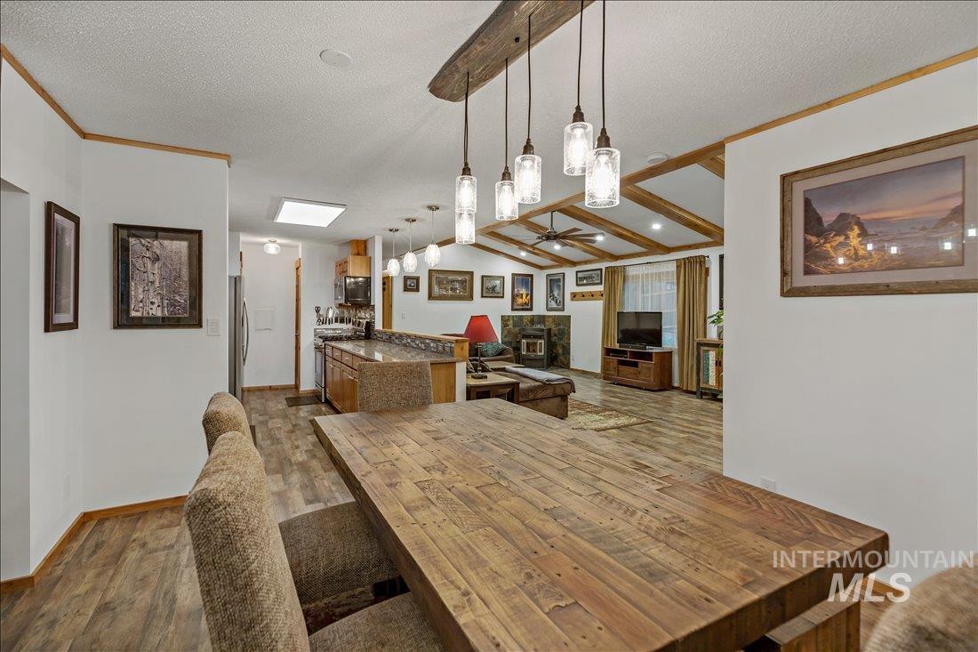 79 Sunset Loop Cascade, ID 83611 - Photo 14 of 44 Open-concept living space featuring wood-finish flooring, exposed beam ceiling accents, a breakfast bar with stone-finish countertop, and a wood-burning stove