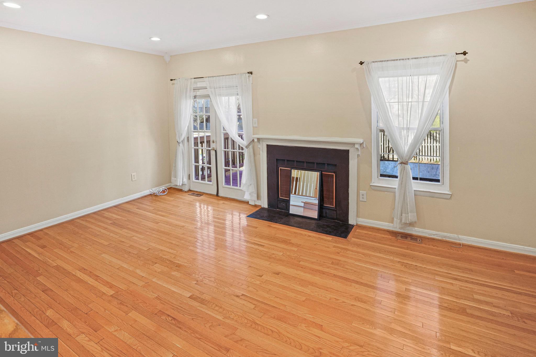 14902 Ashford Place Laurel, MD 20707 - Photo 15 of 41 a view of an empty room with wooden floor fireplace and a window