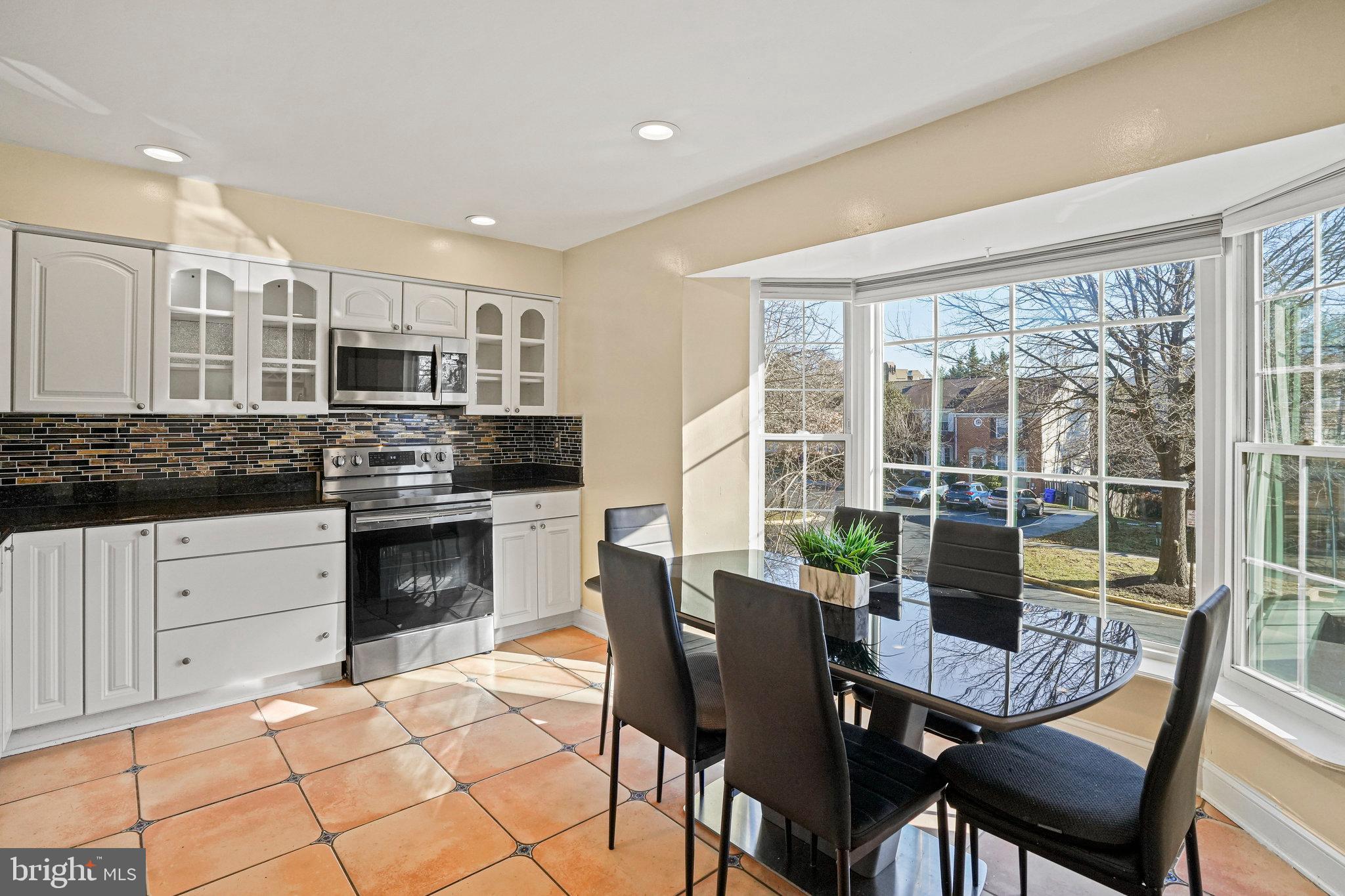 14902 Ashford Place Laurel, MD 20707 - Photo 20 of 41 a kitchen with stainless steel appliances a stove a sink a microwave a dining table and chairs