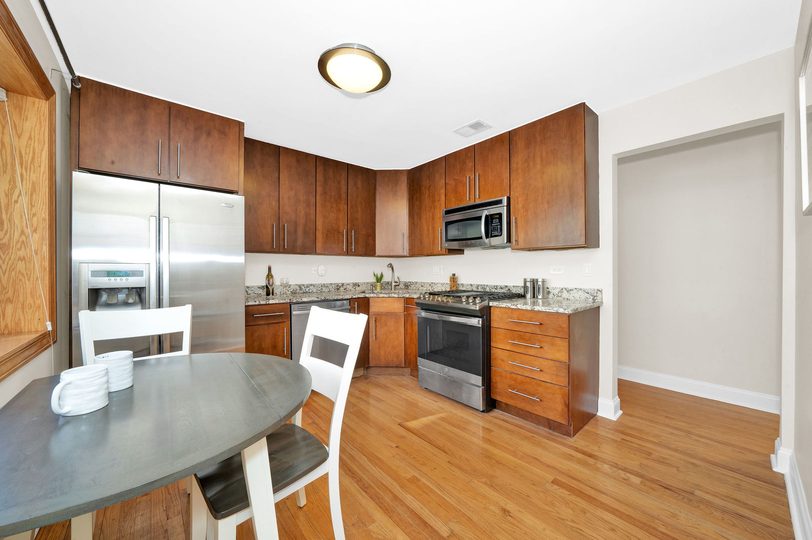 617 South Western Avenue Park Ridge, IL 60068 - Photo 10 of 40 a kitchen with stainless steel appliances granite countertop a stove a refrigerator a sink a dining table and chairs with wooden floor