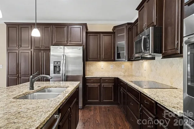 a kitchen with granite countertop a sink stainless steel appliances and cabinets