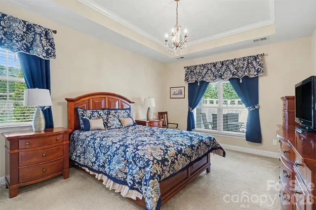 a bedroom with a bed a chandelier and dresser