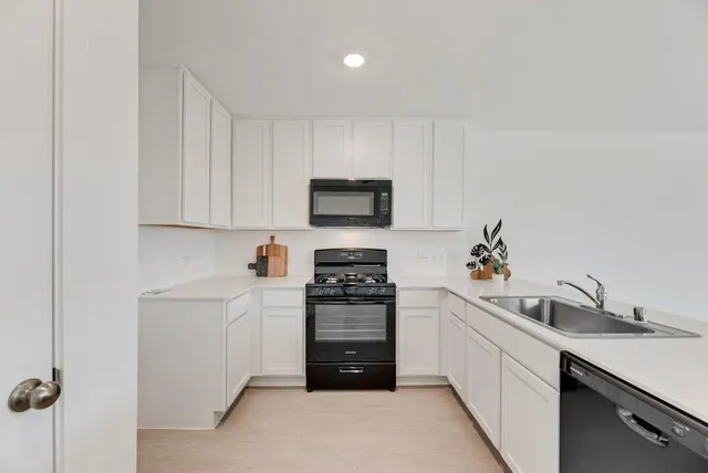 a kitchen with a sink white cabinets and stainless steel appliances