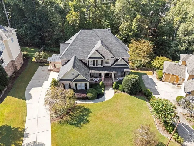 a view of a big house with large trees and plants next to a yard
