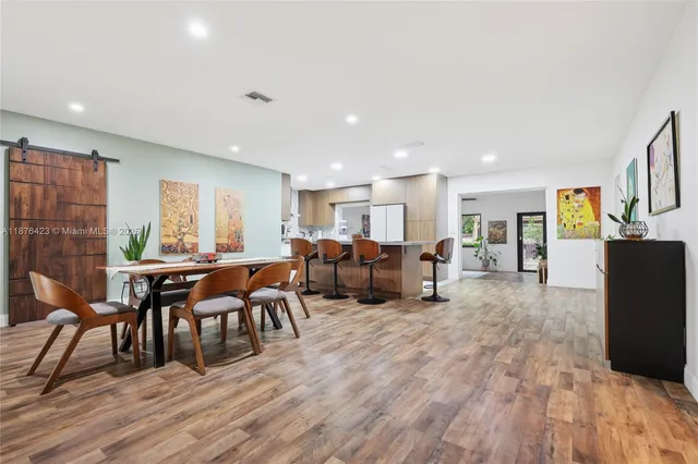 a living room with furniture a dining table wooden floor and a large window