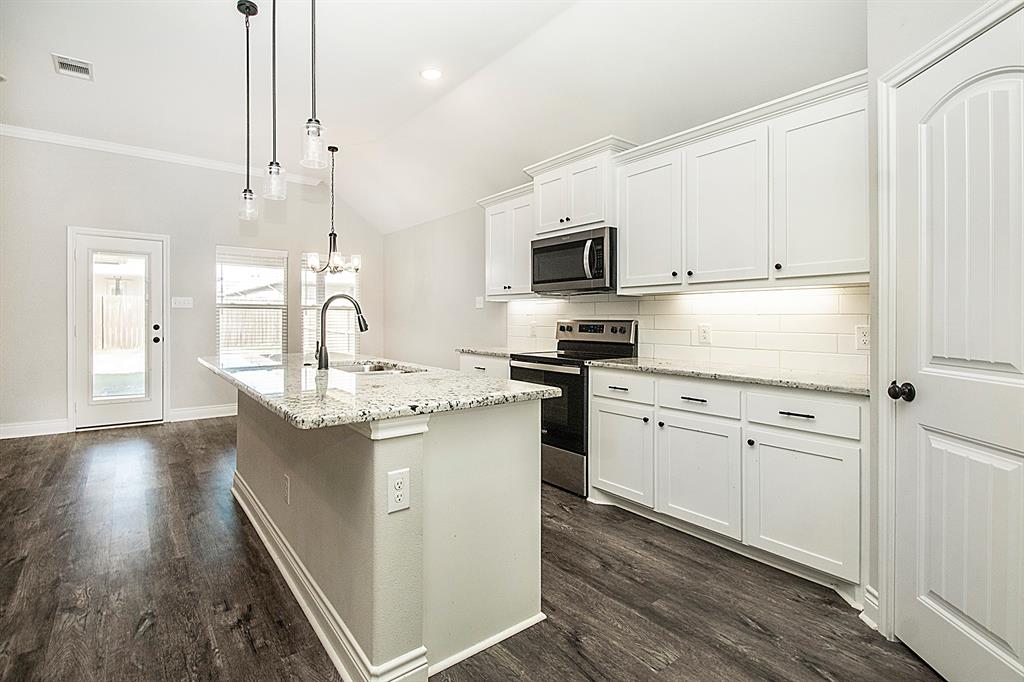 806 Ransom Way Greenville, TX 75402 - Photo 4 of 27 Kitchen featuring a center island with granite-style countertop, stainless steel appliances, white cabinetry, and wood-finish flooring