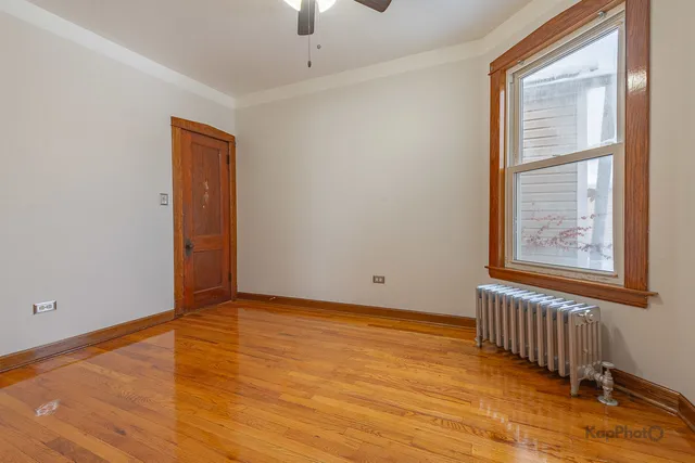 an empty room with wooden floor chandelier fan and windows