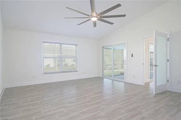 an empty room with wooden floor ceiling fan and windows