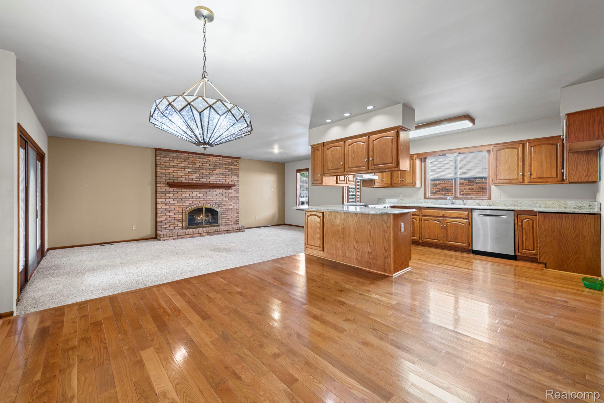 21580 Georgetown Road Trenton, MI 48183 - Photo 8 of 36 Open-concept living area featuring hardwood flooring, a brick-front fireplace, and a kitchen island with seating