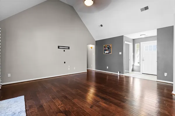 an empty room with wooden floor and windows