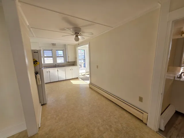a kitchen with granite countertop a refrigerator a sink a stove and white cabinets