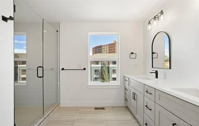 a bathroom with a double vanity sink a mirror and a shower