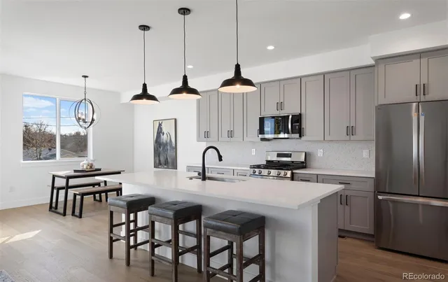 a kitchen with stainless steel appliances a table chairs and a refrigerator
