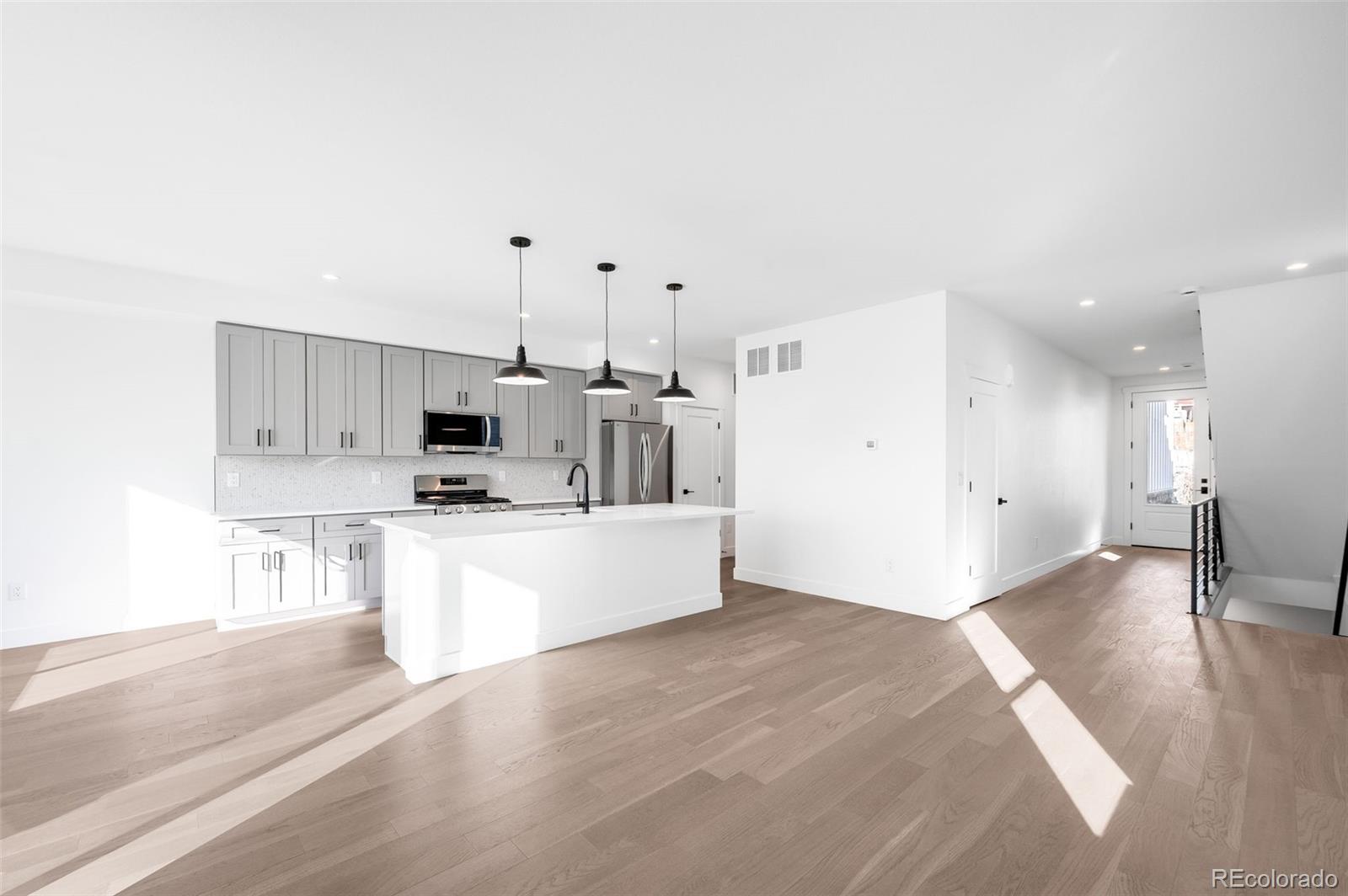 4660 West 9th Avenue Denver, CO 80204 - Photo 3 of 35 a large white kitchen with kitchen island a sink a stove a refrigerator and white cabinets