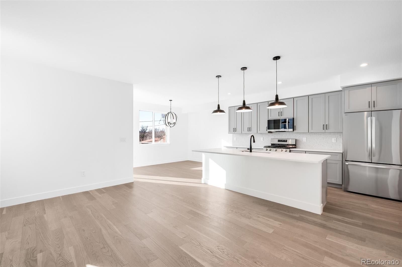4660 West 9th Avenue Denver, CO 80204 - Photo 5 of 35 a kitchen with stainless steel appliances a refrigerator a sink dishwasher a stove and white cabinets with wooden floor