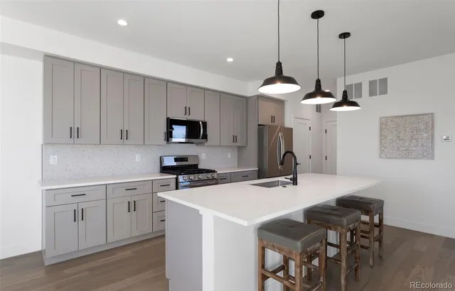 a kitchen with stainless steel appliances a sink a stove a refrigerator and cabinets