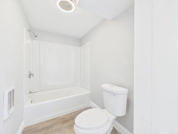 a white toilet sitting next to a bath tub