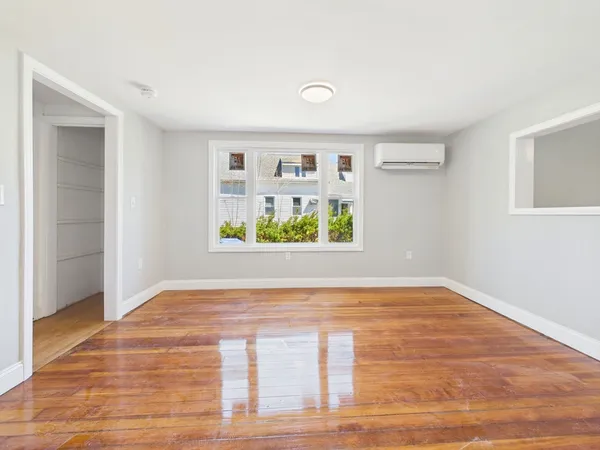 a view of an empty room with window and wooden floor