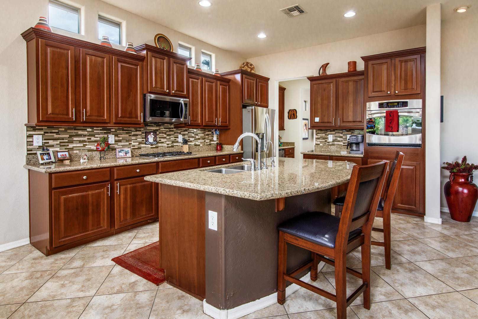 42204 West Rummy Road Maricopa, AZ 85138 - Photo 17 of 79 a kitchen with stainless steel appliances granite countertop a stove a sink dishwasher and a refrigerator with wooden cabinets