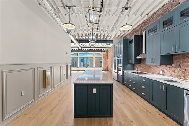 a large room with stainless steel appliances wooden floors and view living room