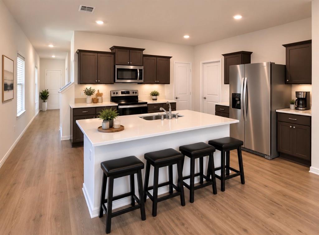816 Country Road Royse City, TX 75189 - Photo 3 of 24 Kitchen featuring an island with a built-in sink, dark wood cabinetry, white countertops, stainless steel appliances, and recessed lighting