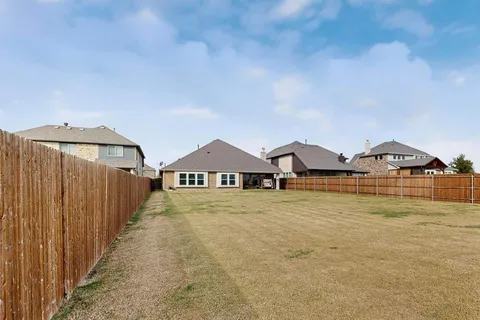 a view of a big house with wooden fence