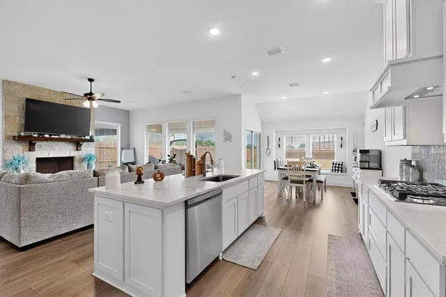 a open kitchen with sink a stove and cabinets with wooden floor