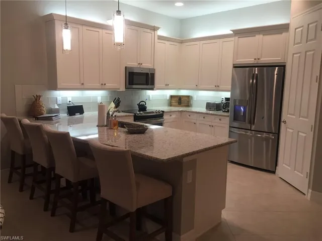 a kitchen with stainless steel appliances granite countertop a table chairs microwave and refrigerator