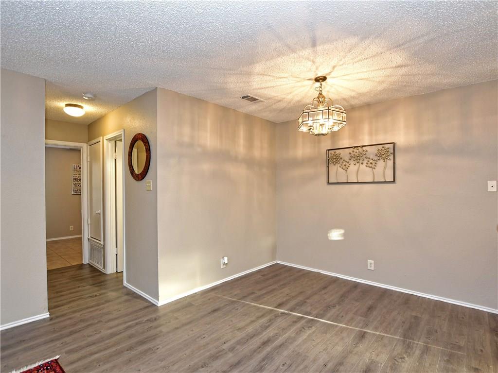 5401 Spring Meadow Road, Unit B Austin, TX 78744 - Photo 6 of 21 A well-lit room showcasing rich flooring and a distinctive overhead lighting fixture.