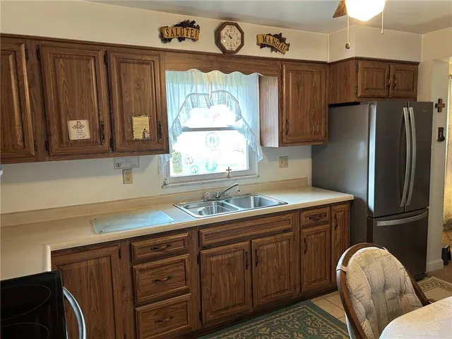 a kitchen with stainless steel appliances granite countertop a sink a refrigerator and wooden cabinets