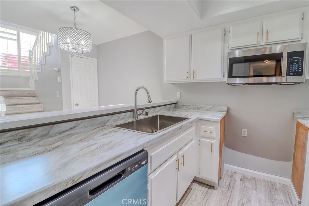 14738 Pioneer Boulevard Norwalk, CA 90650 - Photo 52 of 72 a kitchen with stainless steel appliances granite countertop a sink dishwasher a microwave oven and white cabinets with wooden floor