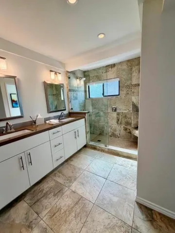 a spacious bathroom with a granite countertop sink a mirror and a bathtub