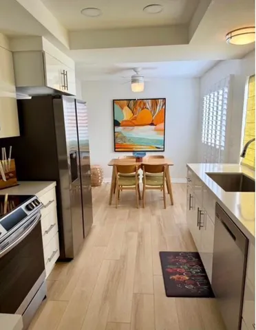 a living room with stainless steel appliances furniture and a flat screen tv