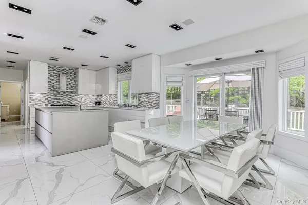 a kitchen with stainless steel appliances kitchen island granite countertop a table chairs sink and cabinets