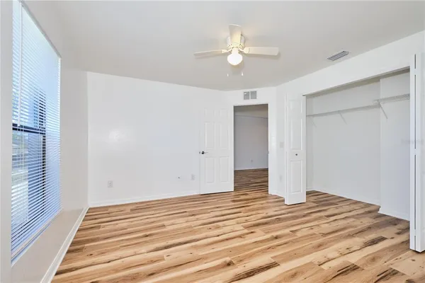 a view of empty room with wooden floor and fan